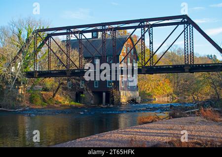 Historisches Mühlenhaus hinter einem verlassenen Eisenbahnbock, der den Raritan River überspannt, an der Neshanic Station, Branchburg, New Jersey, USA, an einem sonnigen Autum Stockfoto