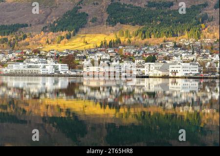 Ein bezauberndes Dorf entlang der Uferpromenade bietet farbenfrohe Häuser und Bäume, die sich an einem Herbsttag wunderschön in stillen Gewässern spiegeln. Stockfoto