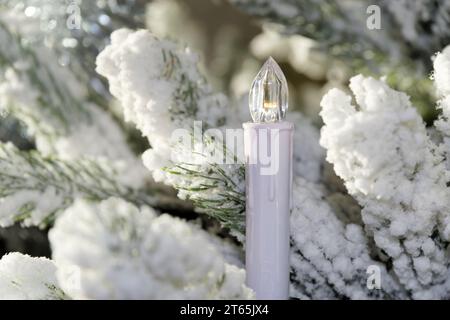 Weihnachtsfestkomposition einer elektrischen Kerze auf einem tannenbaum im Schnee Stockfoto