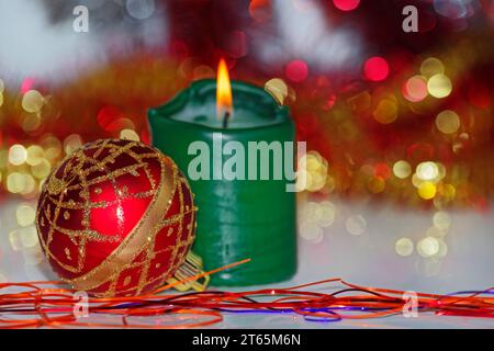 Weihnachtsszene einer roten Kugel und brennende Kerze dagegen Unscharfer Hintergrund Stockfoto