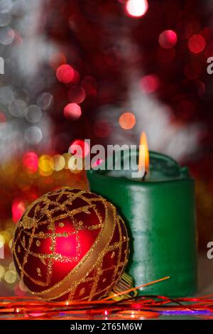 Weihnachtsszene einer roten Kugel und brennende Kerze dagegen Unscharfer Hintergrund Stockfoto