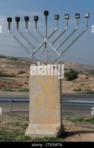 Eine große, achtverzweigte Hanukka-Menora aus Metall, die auf einem Betonfundament errichtet und entlang einer Autobahn im Jordantal in Israel aufgestellt wurde. Stockfoto