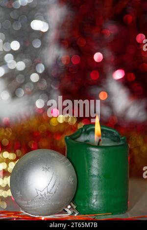 Weihnachtsszene aus silberner Kugel und brennende Kerze gegen verschwommen Hintergrund Stockfoto