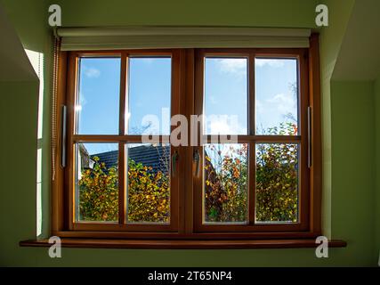 Blick durch einen doppelt verglasten Holzfensterrahmen im Haus bei Herbstwetter Stockfoto