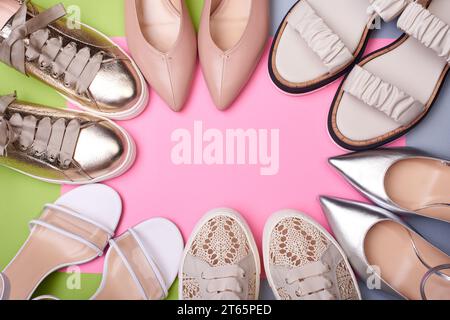 Verschiedene stylische Sommerschuhe für Damen auf dem farbigen Hintergrund. Flach, Draufsicht, Kopierraum in der Mitte. Ein modernes und modisches Schuhgeschäft. Stockfoto