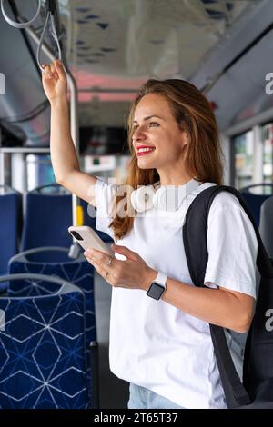 Attraktive junge Frau fährt mit dem Stadtbus. Öffentliche Verkehrsmittel und weibliche Passagiere. Stockfoto