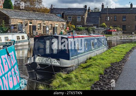 Ein Binnenschiff (Schmalboot, Flachbodenboot) liegt am Leeds Liverpool Canal in Bingley, Yorkshire. Das Café Five Rise Locks ist im Hintergrund. Stockfoto