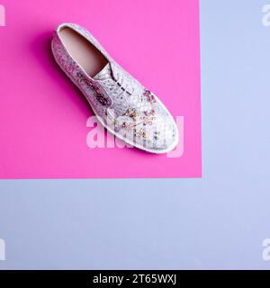 Glamouröser Damenschuh mit Fischschalen in Silber, verziert mit einem mehrfarbigen Strass-Blumenschmuck auf einem grafischen rosa-grauen Hintergrund mit c Stockfoto