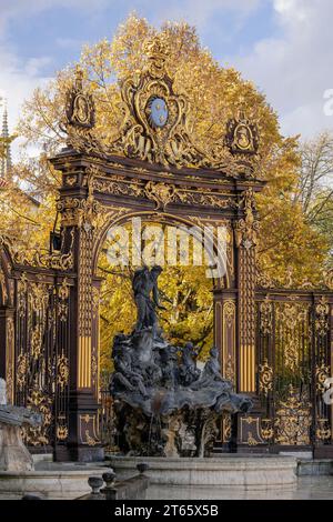 Nancy, Frankreich - der Schwerpunkt liegt auf dem Neptun-Brunnen am Platz Stanislas und Bäumen mit Herbstfarben im Hintergrund. Stockfoto