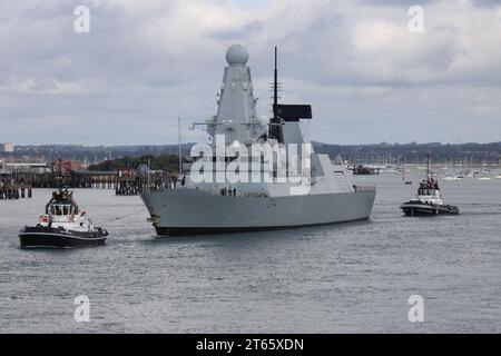 Die HMS DIAMOND DER Royal Navy wird mit GROSSZÜGIGEN und NACHGIEBIGEN Schleppern zur Hafenmündung begleitet, während der Zerstörer die Marinebasis verlässt Stockfoto