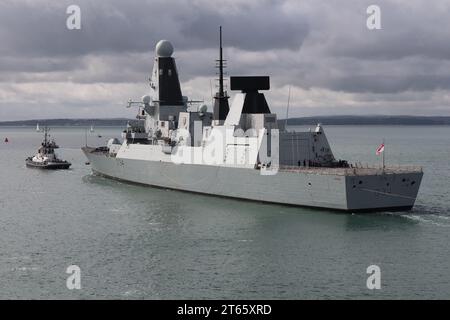 Der Schlepper eskortiert den Royal Navy Type 45 Luftabwehrzerstörer HMS DIAMOND aus dem Hafen Stockfoto