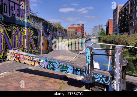 Kingsland: Schleusentore und farbenfrohe Street Art (Graffiti) am Hertford Union Canal mit Booten, Reflexionen und Blick auf Stratford, London, England, Großbritannien Stockfoto