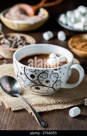 Eine Tasse heißer Kakao mit Marshmallow mit Zutaten im Hintergrund. Stockfoto