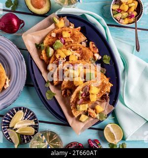 Eine Platte mit hausgemachten knusprigen Fisch-Tacos mit frischer Mangosalsa. Stockfoto