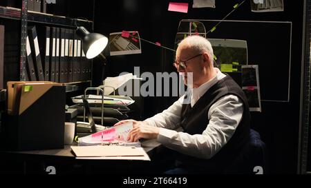 Leitender Detective las geheime Aufzeichnungen im Vorfallsraum, versuchte Verbrechen aufzuklären und versteckte Hinweise aufzudecken. Man Investigator analysiert Zeugenaussagen und forensische Beweisberichte. Stockfoto