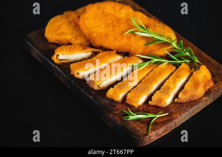 Halbfertiges Hähnchenfilet, Schnitzel.Hühnerpaniertes Schnitzel .Hähnchenfilet auf einem dunklen Hintergrund, Hähnchenpaniertes rohes Fleisch. Schnell Stockfoto