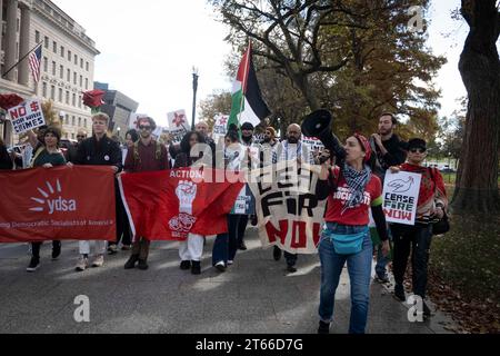 4. November 2023, Washington, District of Columbia, Vereinigte Staaten: Aktivisten der Young Democratic Socialists of America (YDSA) schließen sich einer größeren Koalition von Demonstranten in der Nähe des Washington Monuments an und treten für einen Waffenstillstand im andauernden Konflikt ein. Sie halten Banner mit klaren Forderungen: „WAFFENSTILLSTAND JETZT“ und „KEIN $ FÜR KRIEGSVERBRECHEN“. Sie marschieren am 4. November 2023 in Richtung Freedom Plaza in Washington, DC. Ihre sichtbare Präsenz und ihre lautstarken Handlungsaufrufe stellen eine breite demografische einheit unter dem Pro-palästinensischen Banner dar, die sofortigen Wandel und ein Ende der Feindseligkeiten fordert. (Kreditbild: © Stockfoto