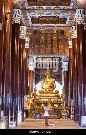 Wat Lok Molee, große, eindrucksvollste Chedis in Chiang Mai. Hohe glänzende dunkle Holzsäulen und kunstvoll geflieste Decke. Der goldene Buddha umgeben von kleinen Stockfoto