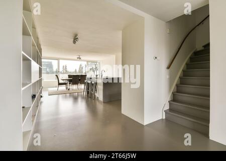 Ein Wohnzimmer mit Treppen, die zur Küche und zum Essbereich auf der linken Seite des Zimmers führen, ist ein offener Grundriss Stockfoto