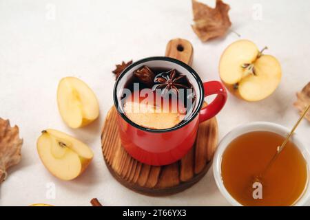 Cup of hot mulled wine with apple and bowl of honey on white background Stock Photo