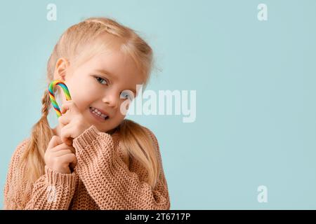 Niedliches kleines Mädchen mit bunten Zuckerrohr auf blauem Hintergrund Stockfoto