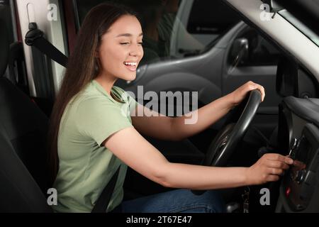 Auswählen des bevorzugten Funkgeräts. Schöne Frau, die im Auto den Knopf auf das Audio drückt Stockfoto