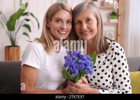 Glückliche reife Mutter und Tochter mit schönen Kornblumen zu Hause Stockfoto