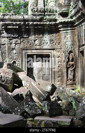 Geschnitzte Steinreliefs bedecken die Wände dieses Tempelrestes im archäologischen Park Angkor in Kambodscha. Eine Devata-Figur ist neben dem Eingang geschnitzt Stockfoto