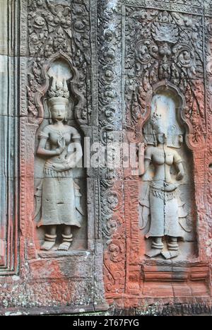 Devata-Figuren aus Stein zieren eine Mauer im archäologischen Park Angkor in Kambodscha. Überreste alter roter Ocker-Farben das kunstvolle Basrelief Stockfoto