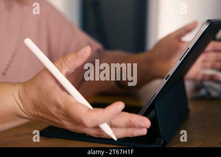Unerkennbare Frauenhand mit einem Grafiktablett-Computer mit Stift-Stift in einem Café. Zugeschnittene Aufnahme einer Frau, die auf einem digitalen Touchscreen arbeitet DE Stockfoto
