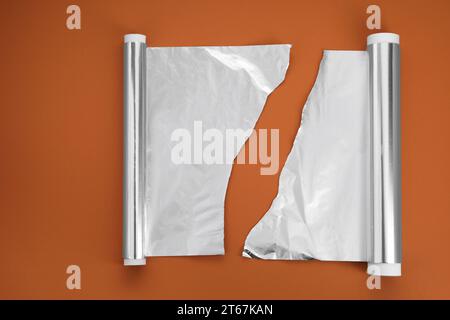 Rollen aus Aluminiumfolie auf braunem Hintergrund, flache Lagen Stockfoto