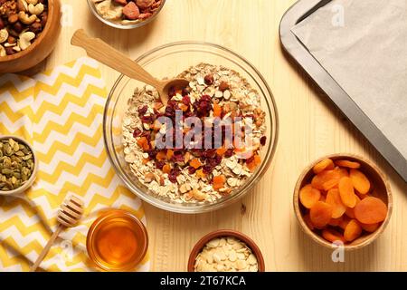 Müsli machen. Haferflocken, getrocknete Aprikosen und andere Zutaten auf Holztisch, flach gelegt Stockfoto