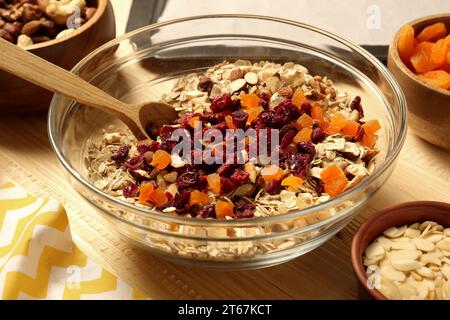 Müsli machen. Haferflocken, getrocknete Aprikosen, Nüsse und Kirschen in Schüssel auf dem Tisch, Nahaufnahme Stockfoto