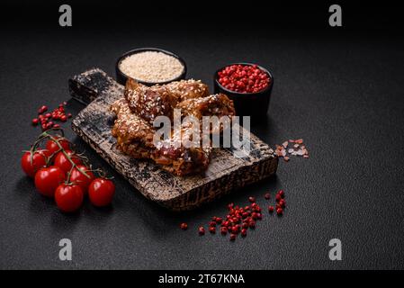 Köstliche gegrillte Hähnchenflügel mit Salz, Gewürzen und Teriyaki-Sauce auf dunklem Betonhintergrund Stockfoto