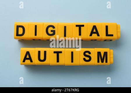 Phrase Digital Autismus aus gelben Würfeln auf hellblauem Hintergrund, flache Lay. Suchtverhalten Stockfoto