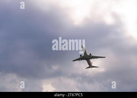 Nahaufnahme eines weißen Passagierflugzeugs, das gegen einen grauen bedeckten Himmel abhebt. Reisen Sie mit dem Flugzeug Stockfoto