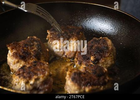 Nahaufnahme von frittierten Hackfleischkoteletts in einer Pfanne. Der Koch dreht die Schnitzel in der Pfanne mit einer Gabel. Russische oder polnische Version der Schnitzel - kotlety. Stockfoto