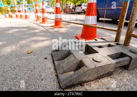 Barrikade vor der Baustelle neben der Stadtstraße mit aktivem Verkehr installiert. Mobiler Metallzaun mit Kunststofffuß sorgt für Stabilität der Tempora Stockfoto