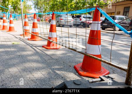 Barrikade vor der Baustelle neben der Stadtstraße mit aktivem Verkehr installiert. Mobiler Metallzaun mit Kunststofffuß sorgt für Stabilität der Tempora Stockfoto