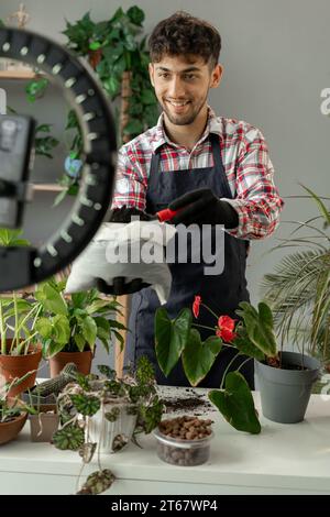 Arabische männliche Gärtner Influencer Filme Video für Blog gibt Empfehlungen, wie man Topfblume transplantiert Stockfoto