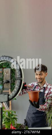 Arabische männliche Gärtner Influencer Filme Video für Blog gibt Empfehlungen, wie man Topfblume transplantiert, Gießen Drainage sendet Livestream Stockfoto