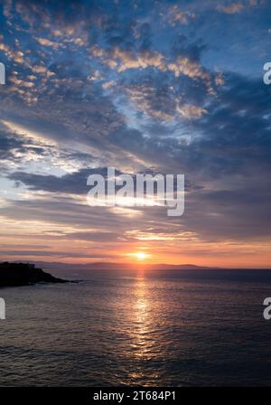 Sonnenuntergangslandschaft zwischen den Wolken über dem Horizont des Meeres. Goldene Reflexionen in den Wolken und im Meer. Stockfoto