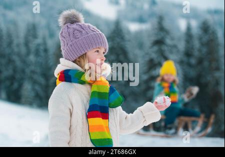 Kleine Mädchen und Jungen genießen einen Tag im Winterwald spielen. Kinder Geschwister haben Spaß im schönen Winterpark. Frohe Kindheit. Stockfoto