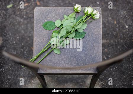 Leipzig, Deutschland. November 2023. Drei weiße Rosen liegen auf einem Bronzesessel im Leipziger Synagogendenkmal. An diesem Tag finden an vielen Orten in Sachsen Mahnwachen, Gottesdienste und Versammlungen statt, um der Zerstörung jüdischer Geschäfte und Gotteshäuser und der Opfer des Holocaust zu gedenken. In der Nacht vom 9. Auf den 10. November 1938 wurden unter der Leitung des nationalsozialistischen Regimes im ganzen Reich Synagogen und Tausende von Vorräten und Häusern jüdischer Menschen gestürmt und zerstört. Quelle: Jan Woitas/dpa/Alamy Live News Stockfoto