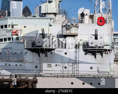 Ein riesiger roter Mohn auf der HMS Belfast, gebaut für die Royal Navy, heute als Museumsschiff an der Themse, London, England, im November 2023. Stockfoto