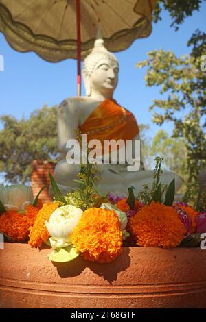Nahaufnahme des Haufens von Ringelblume und Lotus für die Opfer mit verschwommenem weißem Buddha-Bild im Hintergrund, Thailand Stockfoto