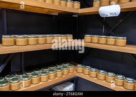 Gläser mit Creme auf dem Verkaufsregal mit Preisschild unter dem Glas auf schwarzem Hintergrund Stockfoto