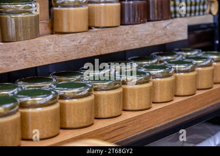 Gläser mit Creme auf dem Verkaufsregal mit Preisschild unter dem Glas auf schwarzem Hintergrund Stockfoto