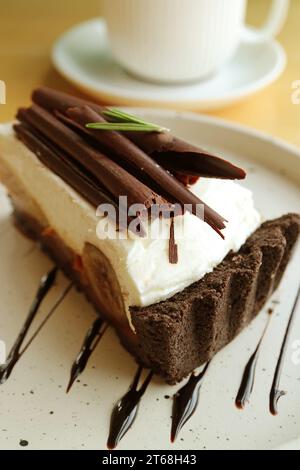 Köstlicher Banoffee Pie mit verschwommenem Glas Heißgetränk im Hintergrund Stockfoto