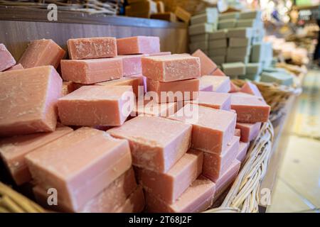 Handgemachter Korb voller handgemachter Blumenseife in einem Geschäft besteht aus Körperpflegeprodukten mit hölzernem Hintergrund Stockfoto